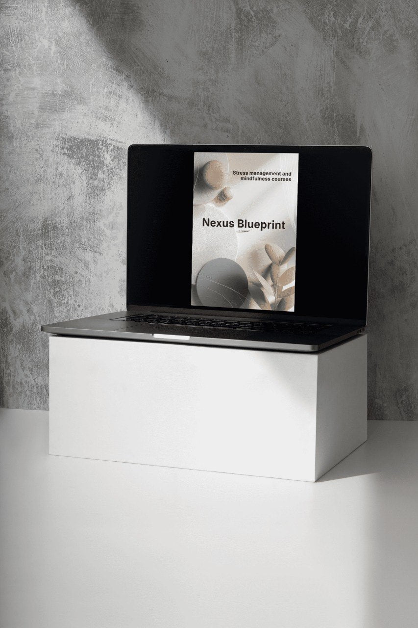 Laptop on a white stand with a Nexus Blueprint book on the screen against a gray concrete wall.